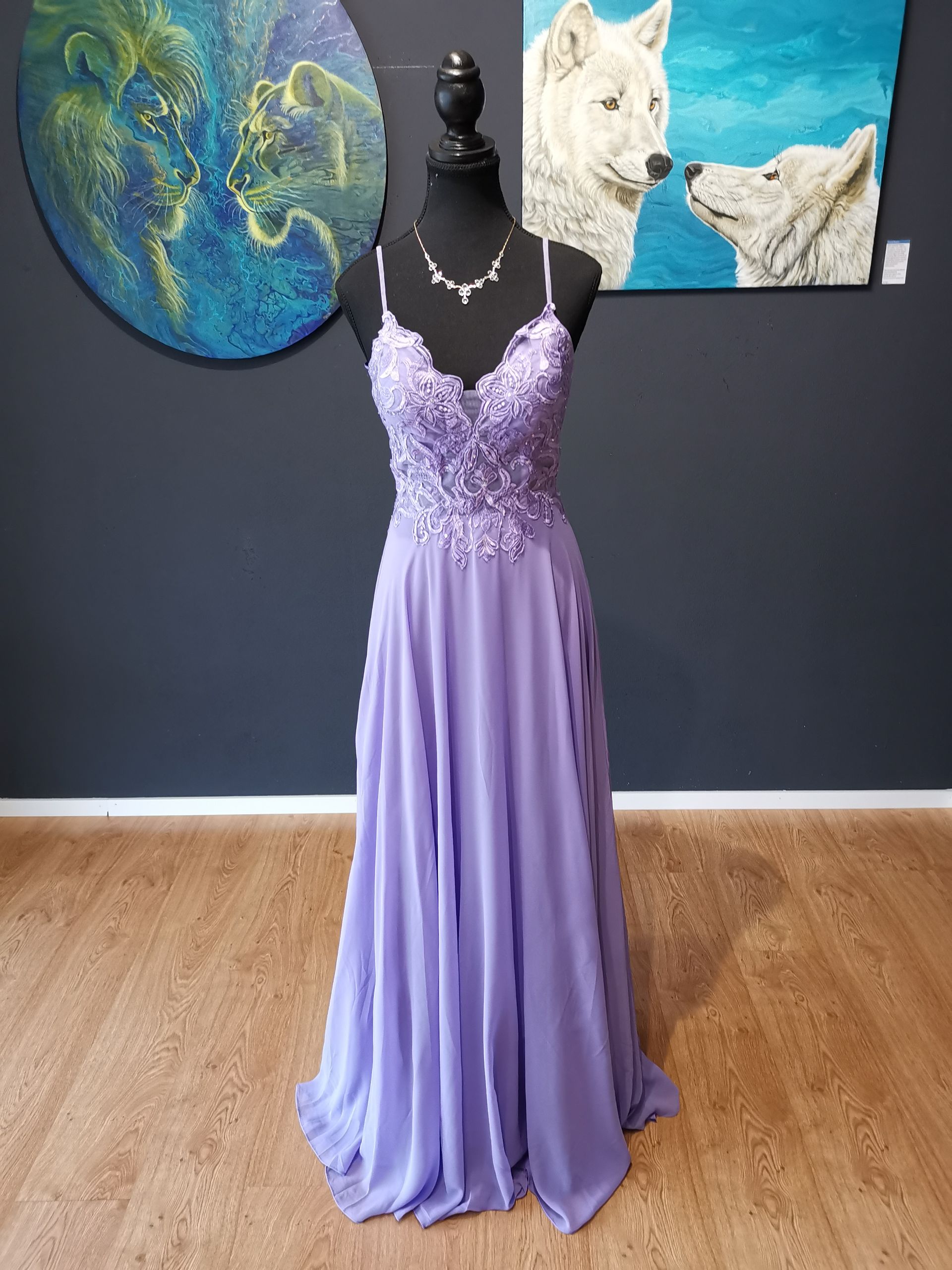Abendkleid in Lavendel auf einer schwarzen Schaufensterpuppe in einem Raum mit Wolfsgemälden und Holzboden