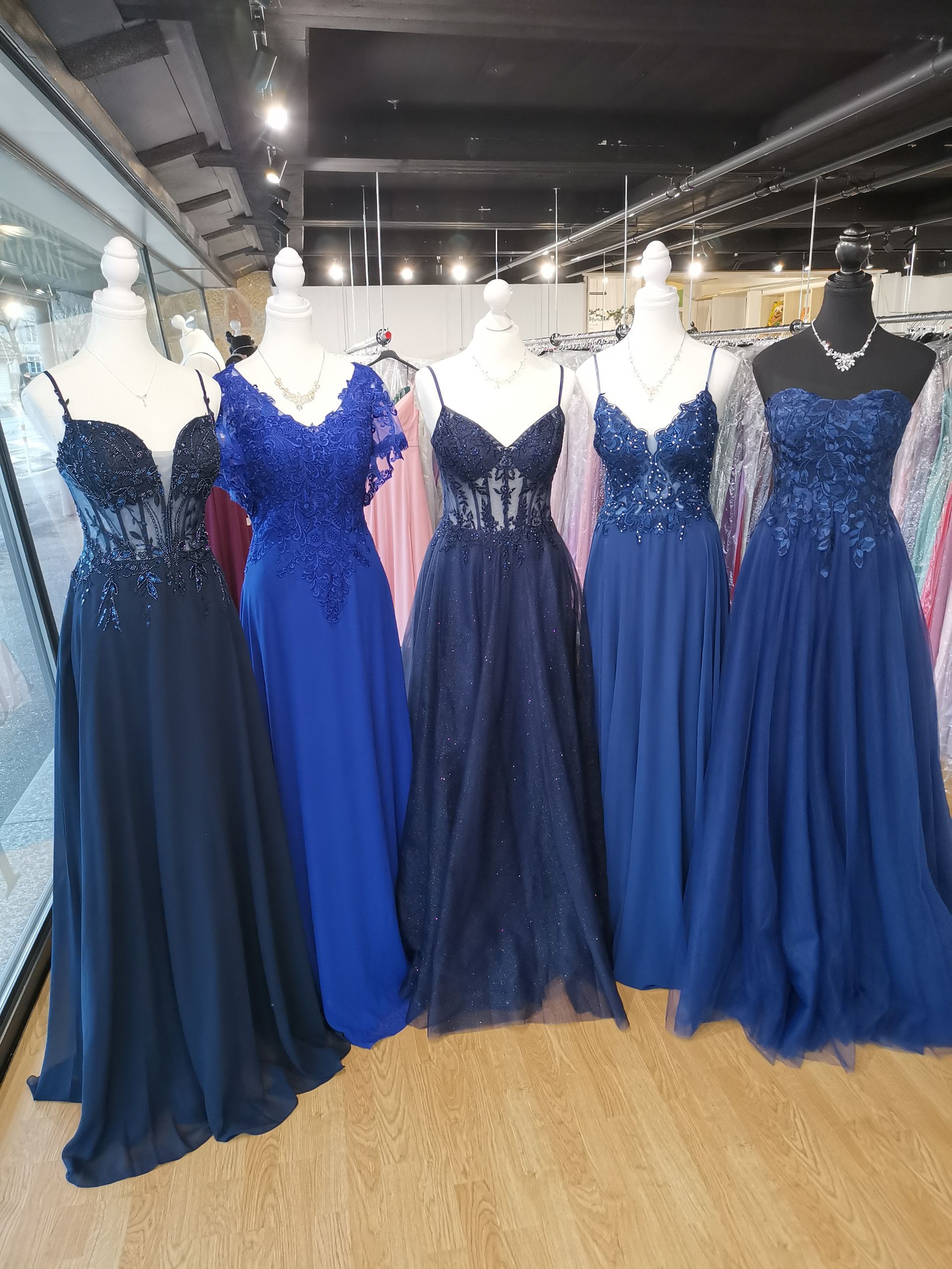 In einer Brautboutique werden blaue und marineblaue Abendkleider auf Schaufensterpuppen ausgestellt.