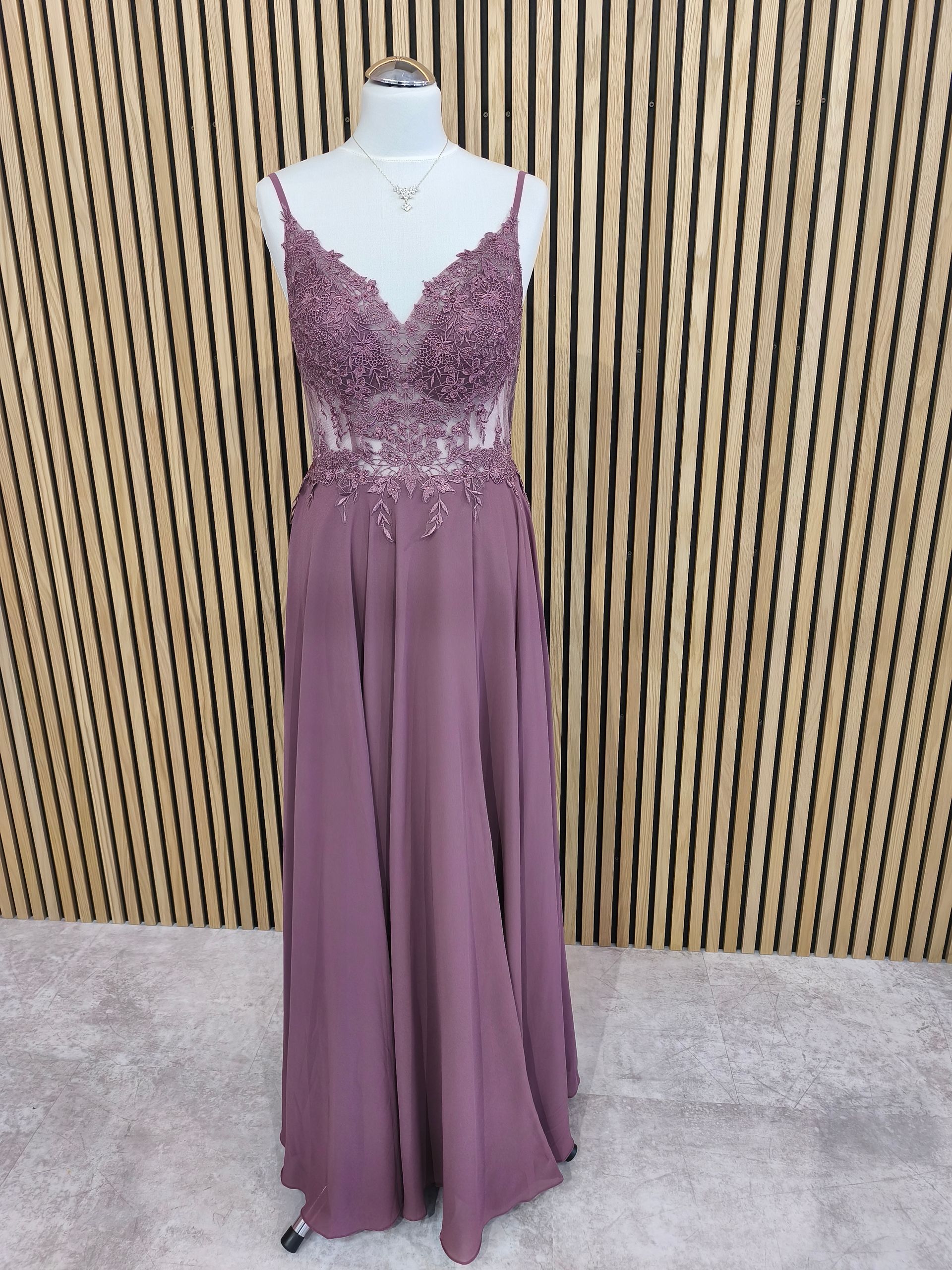 Mauvefarbenes, ärmelloses Abendkleid auf einer Schaufensterpuppe vor einer Holzlattenwand