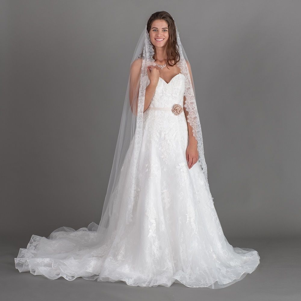Braut in weißem Hochzeitskleid und Schleier vor grauem Hintergrund