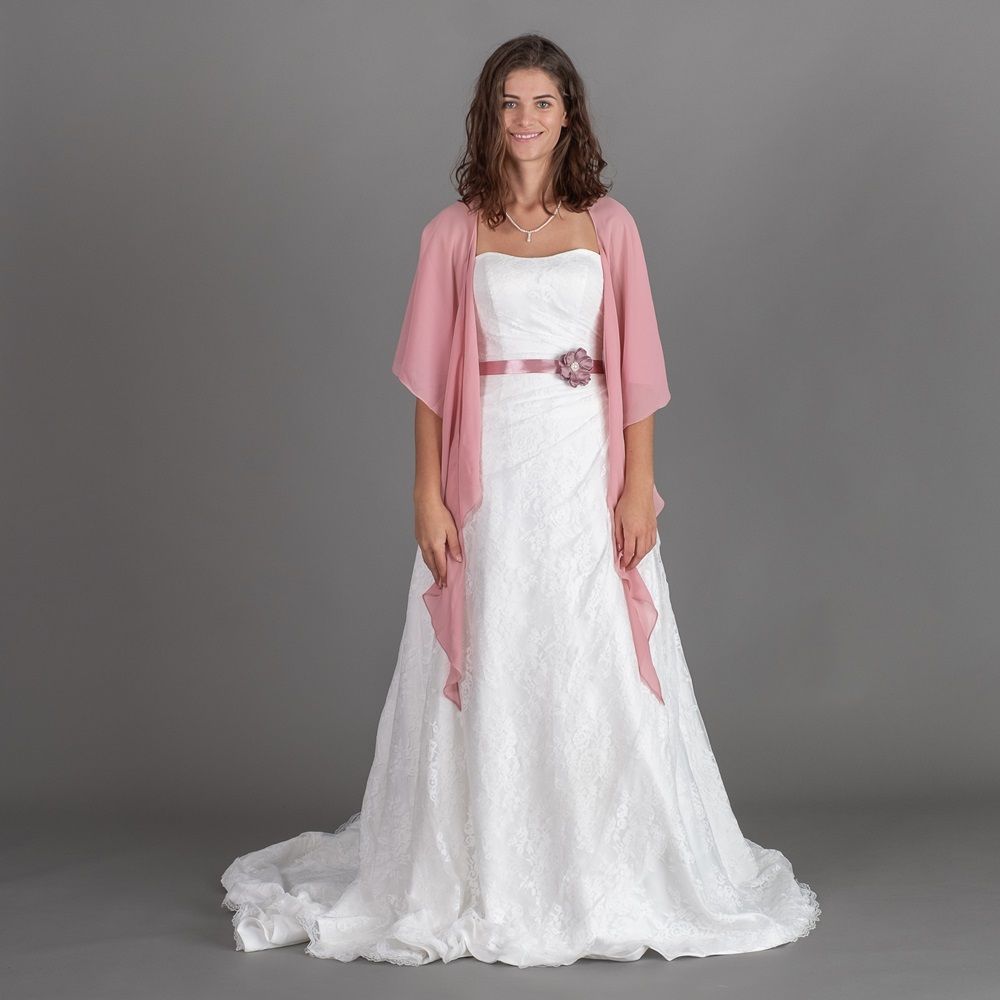 Frau in einem weißen Kleid mit einem rosa Schal vor einem grauen Hintergrund