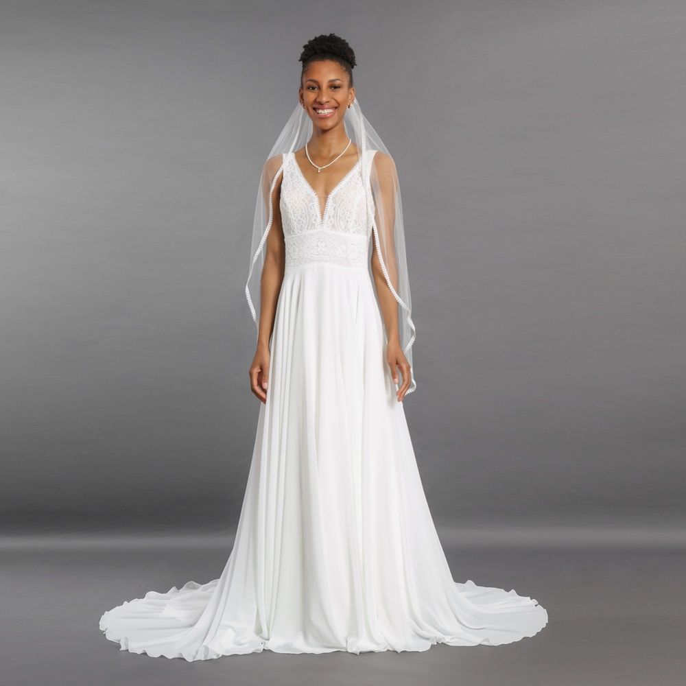 Braut in weißem Hochzeitskleid und Schleier vor grauem Studiohintergrund