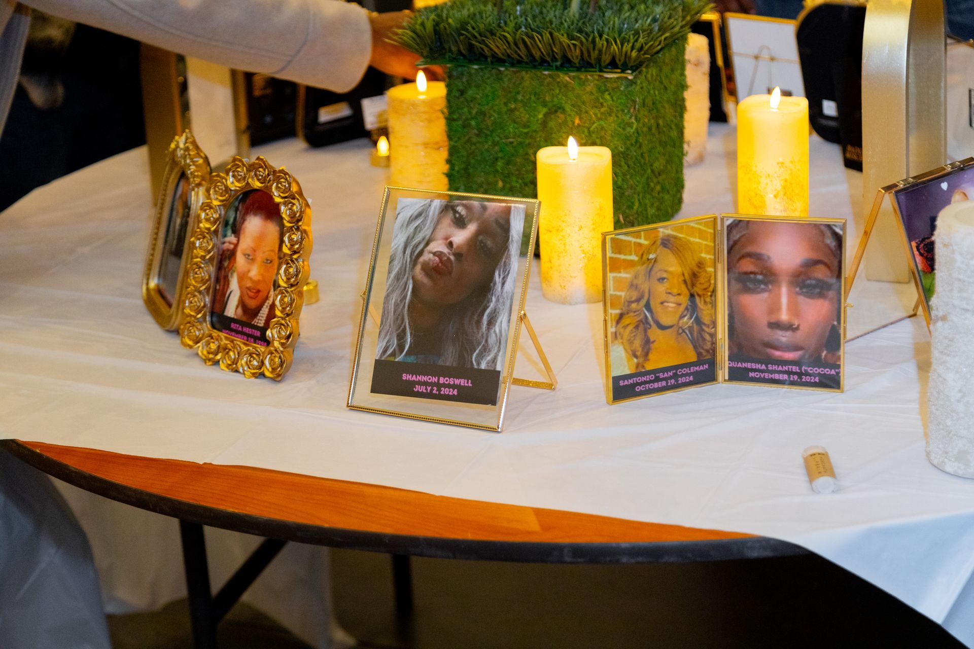 Memorial table with framed photos and yellow candles on a white cloth