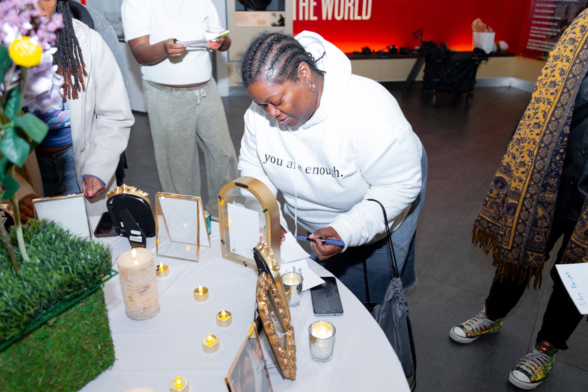 Person leaning over a memorial table with candles and framed photos at an indoor event