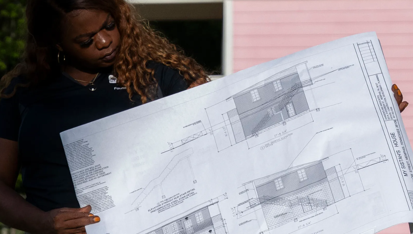 Woman holding a large printed document and looking down at it indoors