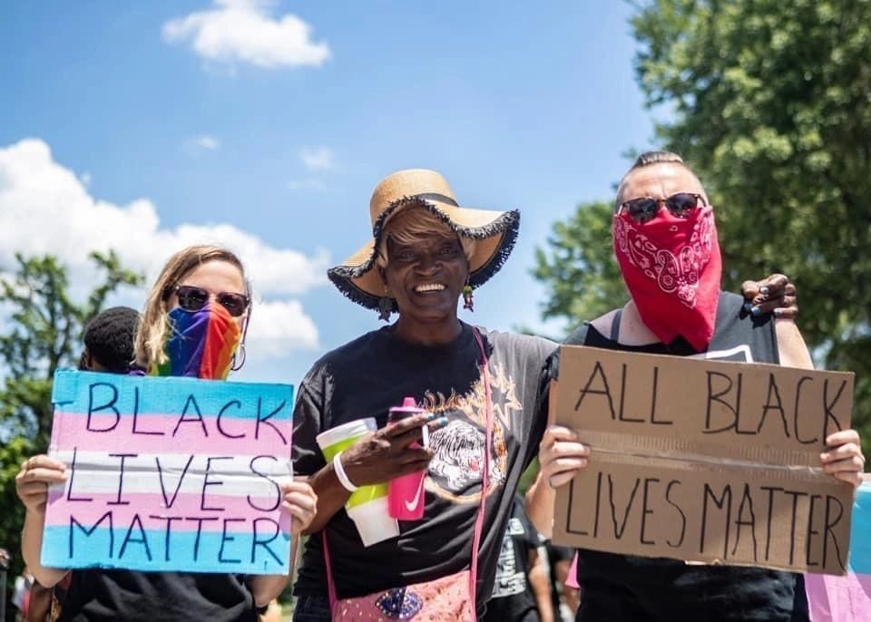 Three protesters holding signs reading “BLACK LIVES MATTER” and “ALL BLACK LIVES MATTER” outdoors.