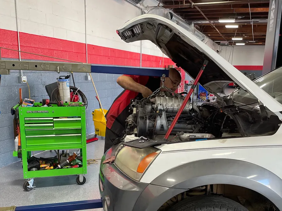 A man is working on the engine of a car in a garage.