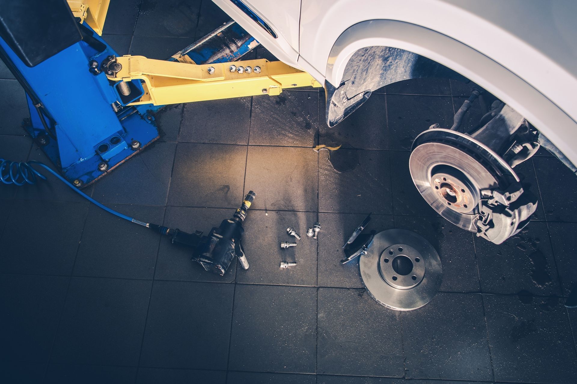 A car is being repaired on a lift in a garage.