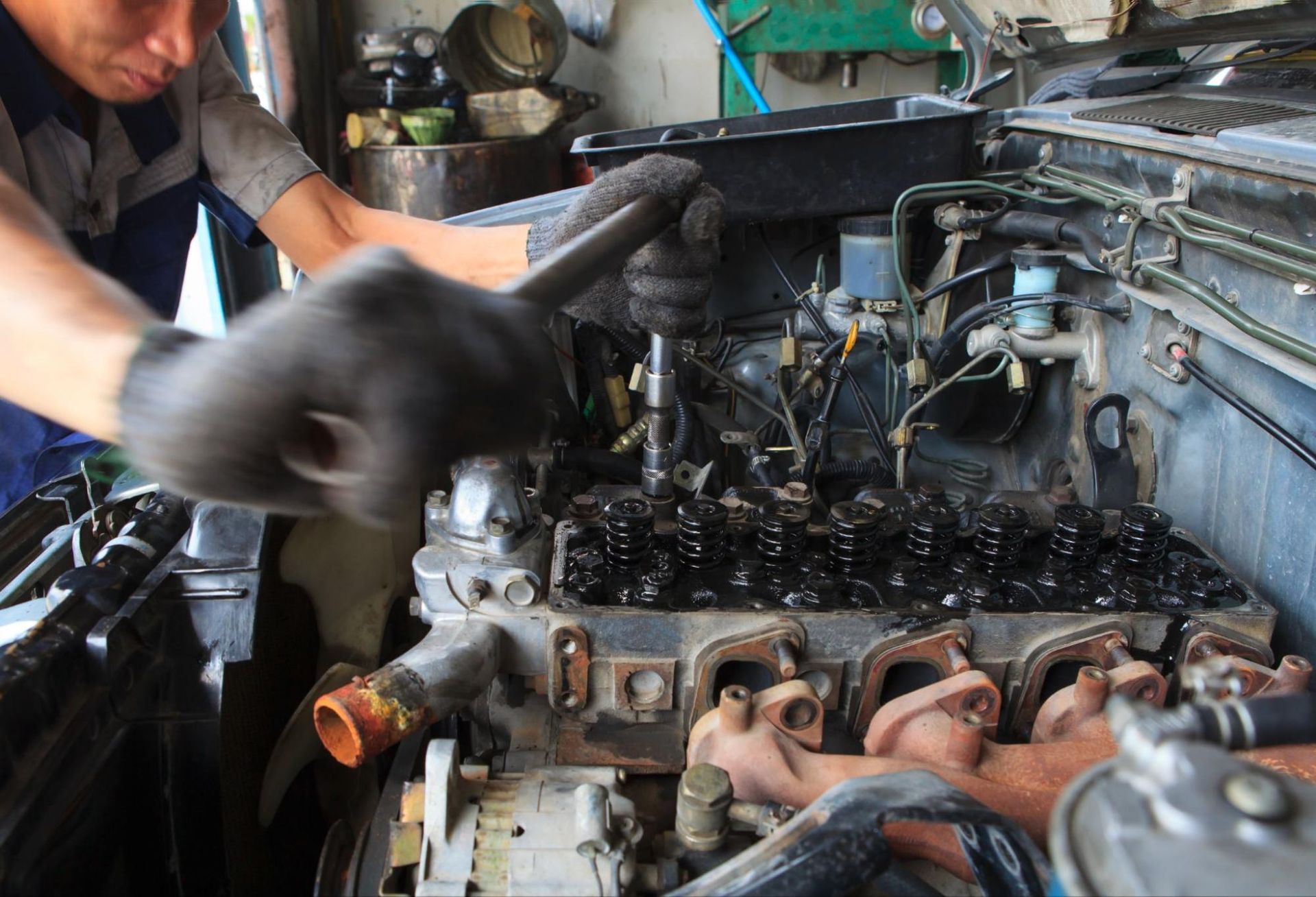 A man is working on a car engine with a wrench.