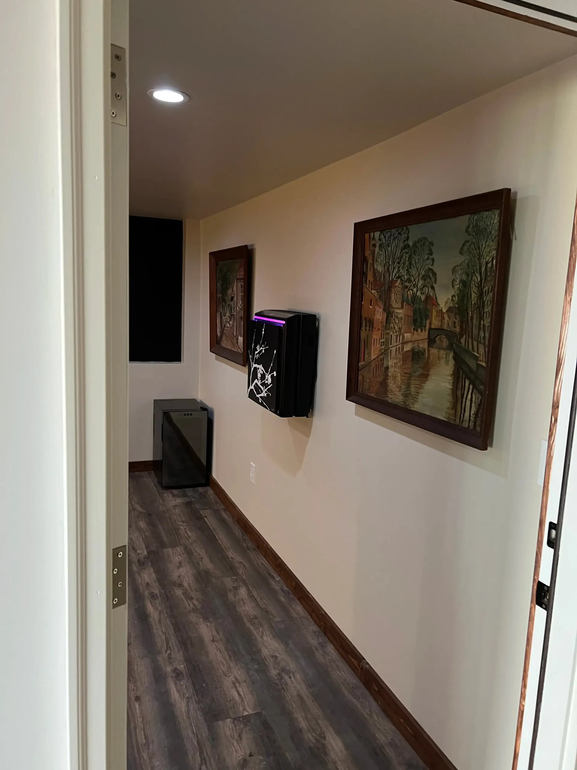 Two chairs and a small table arranged beneath a wall-mounted fireplace on a dark accent wall in a room with wood flooring.
