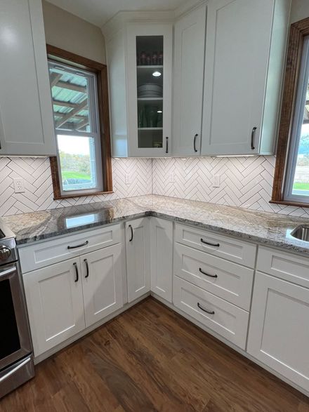 A home bar with wooden cabinets, speckled granite countertops, a built-in black mini fridge, and a wall-mounted TV.