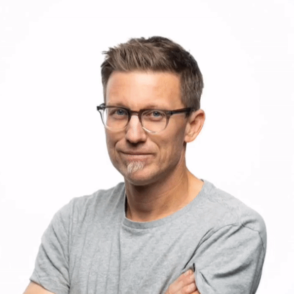 Christopher Todd and Orange County Photographer in a blue shirt is holding a camera and smiling.