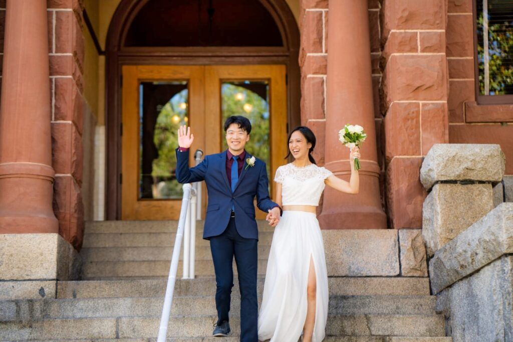 A bride and groom are walking down the stairs of the Old Courthouse