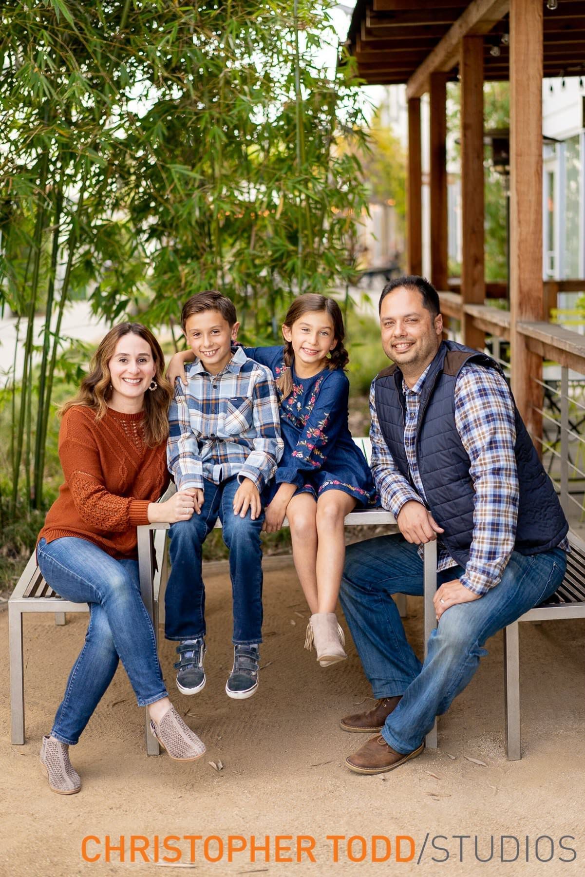 A family is posing for a picture while sitting on a bench in Costa Mesa. 