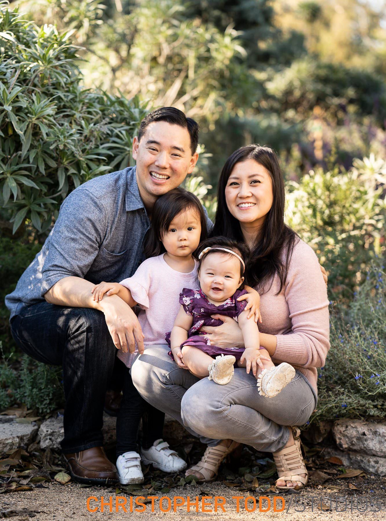 A young family is posing for a picture together in a park.