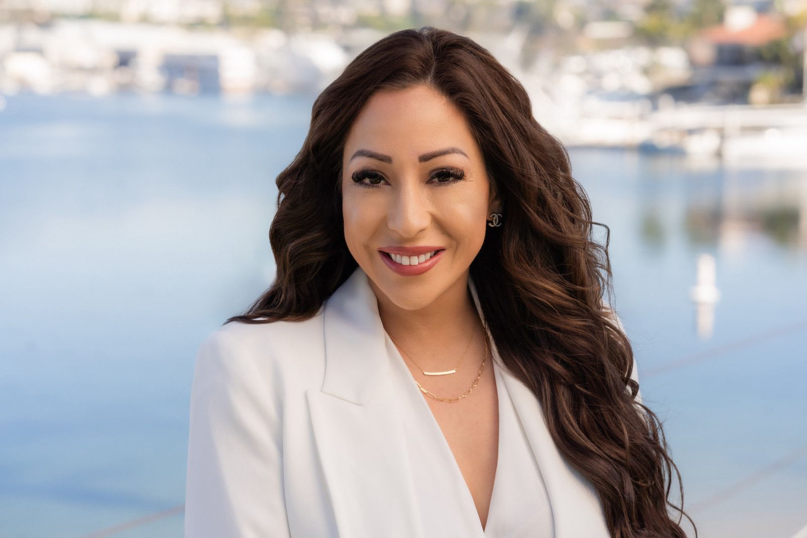 Smiling woman in a white blazer standing by the water with boats in the background newport beach ca realtor