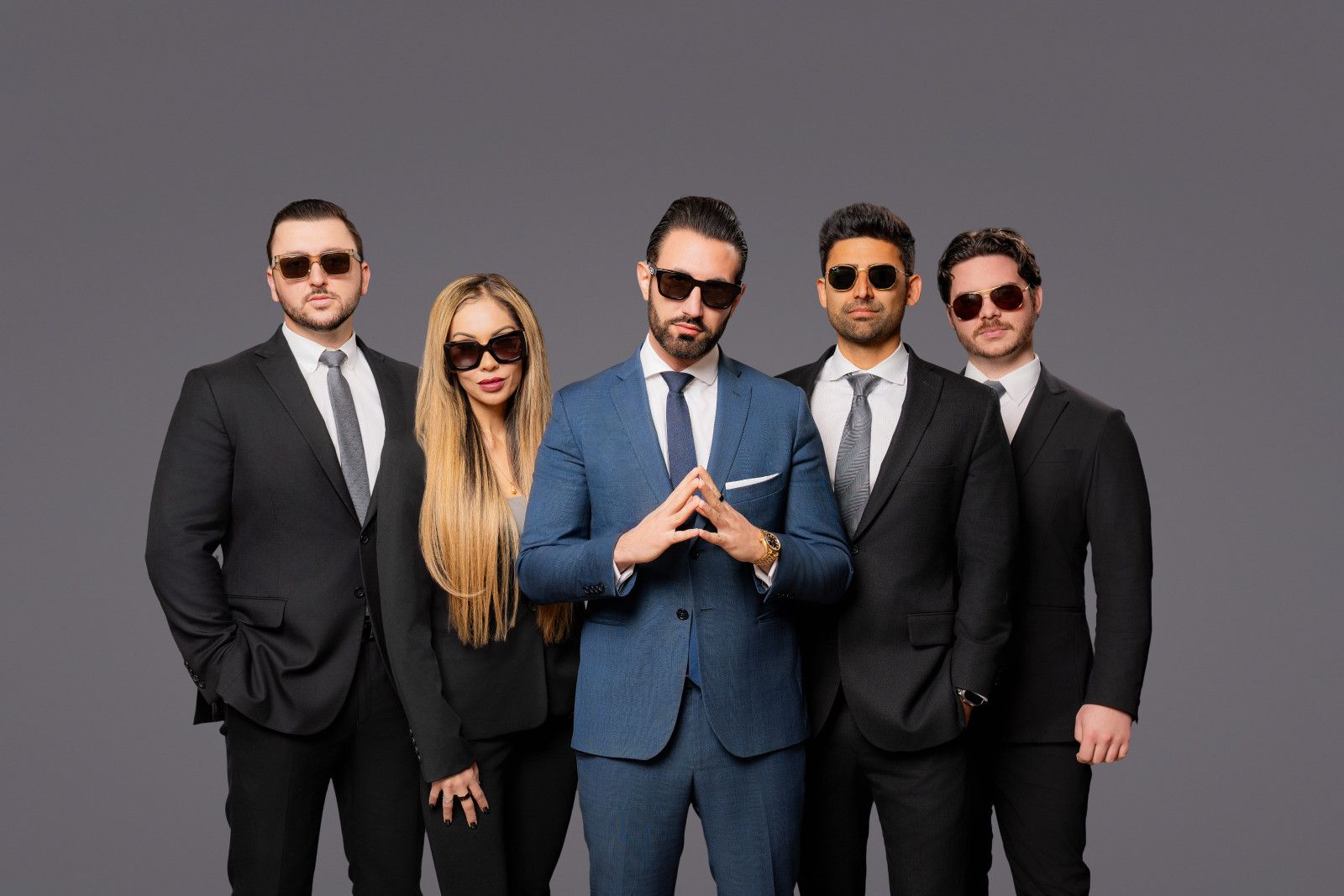 Five people in suits and sunglasses posing against a gray studio background for an Irvine law firm