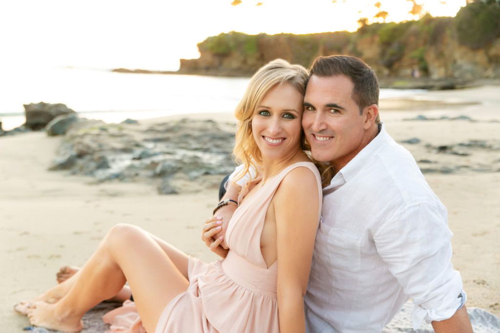 A man and a woman are sitting on a blanket on Laguna beach.
