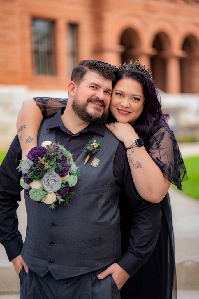 A bride and groom are posing for a picture in front of the Old Courthouse