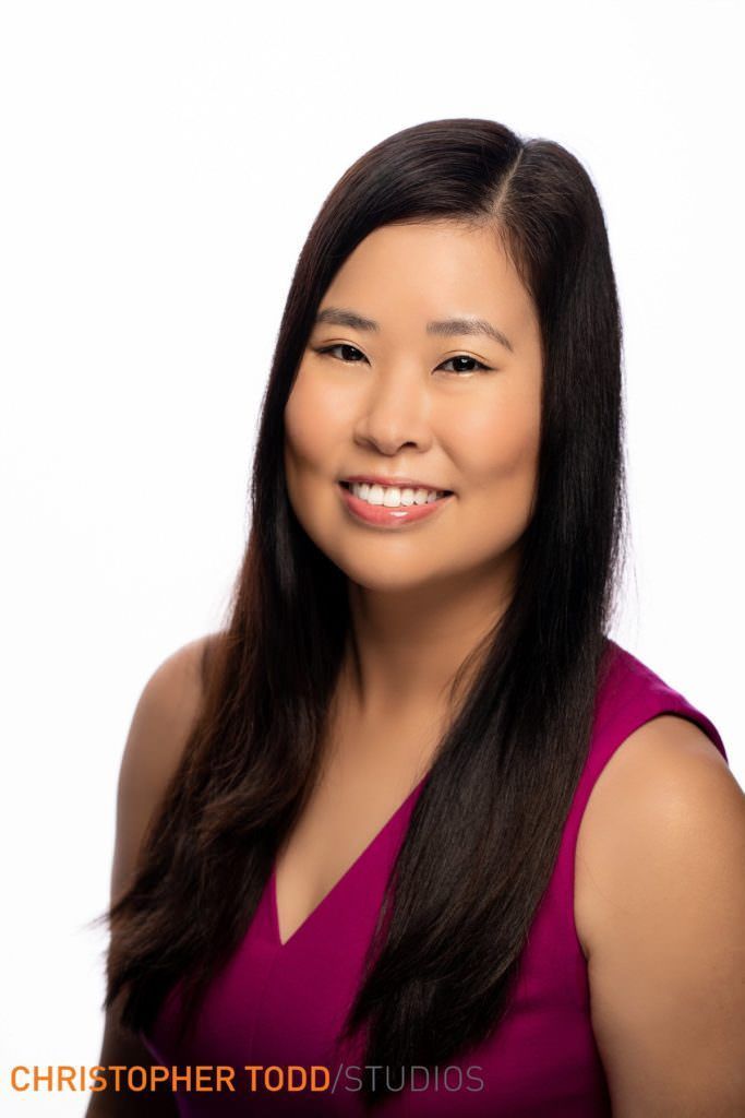 A woman in a purple shirt is smiling for the camera.