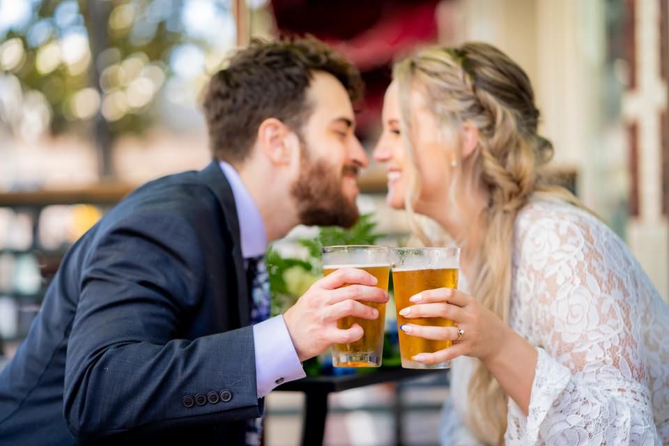 A bride and groom are kissing while holding beer glasses on Main Street in Santa Ana.