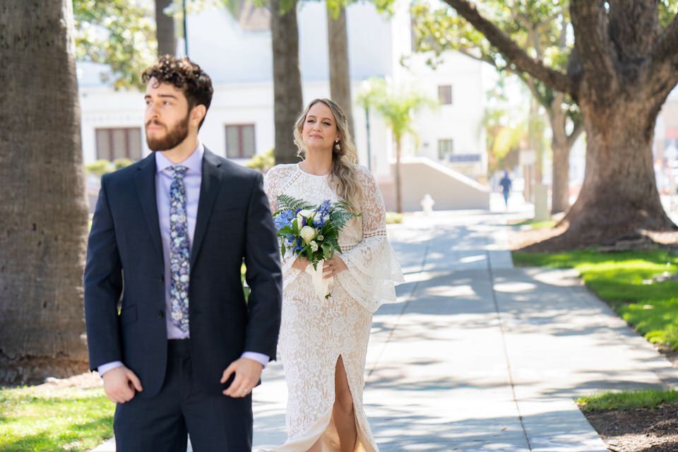 A bride and groom are walking down a sidewalk.
