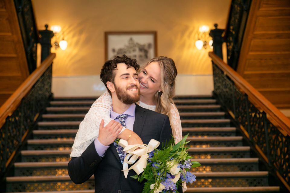 A bride and groom are posing for a picture on a set of stairs.