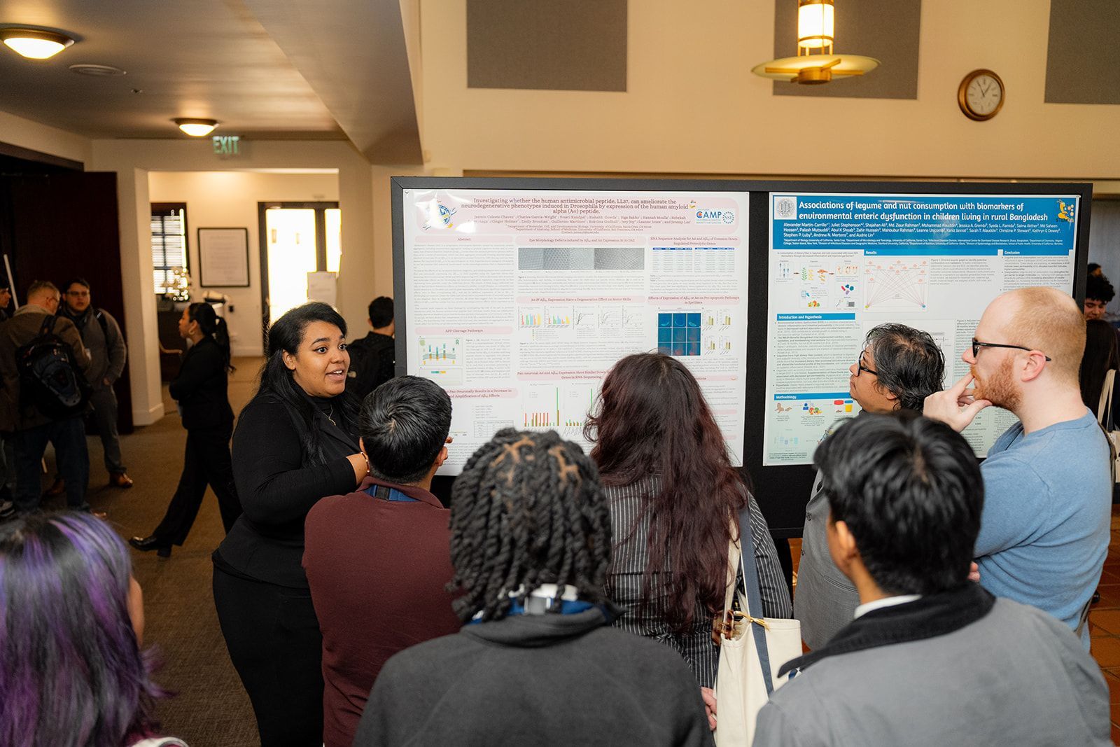 People viewing posters during a presentation in a hallway, with one blue display and one white display at UCI