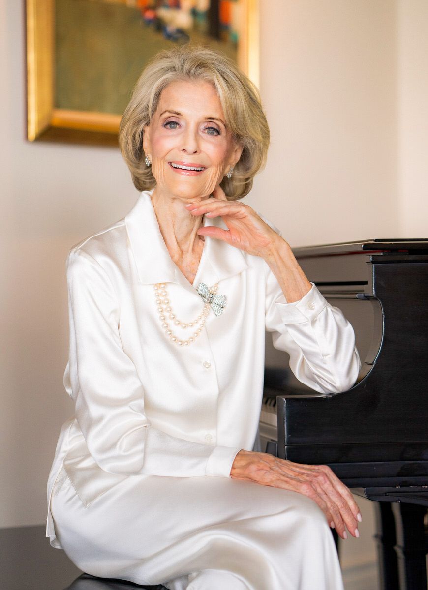 Brand Photography A woman in a white dress is sitting at a piano