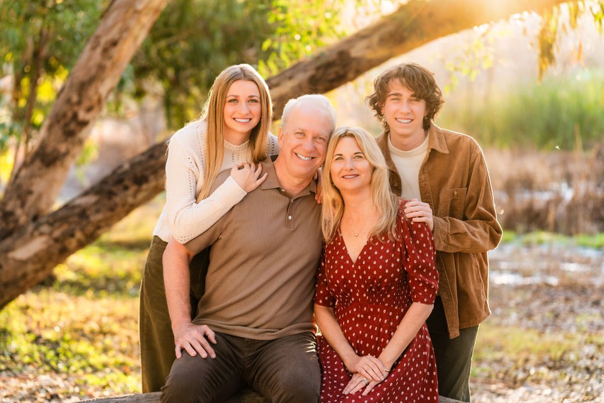 A family is posing for a picture under a tree.