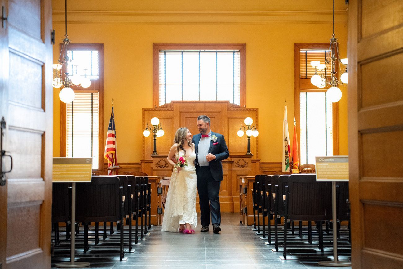 A bride and groom are standing in the historic courtroom in the Old Orange County Courthouse. 