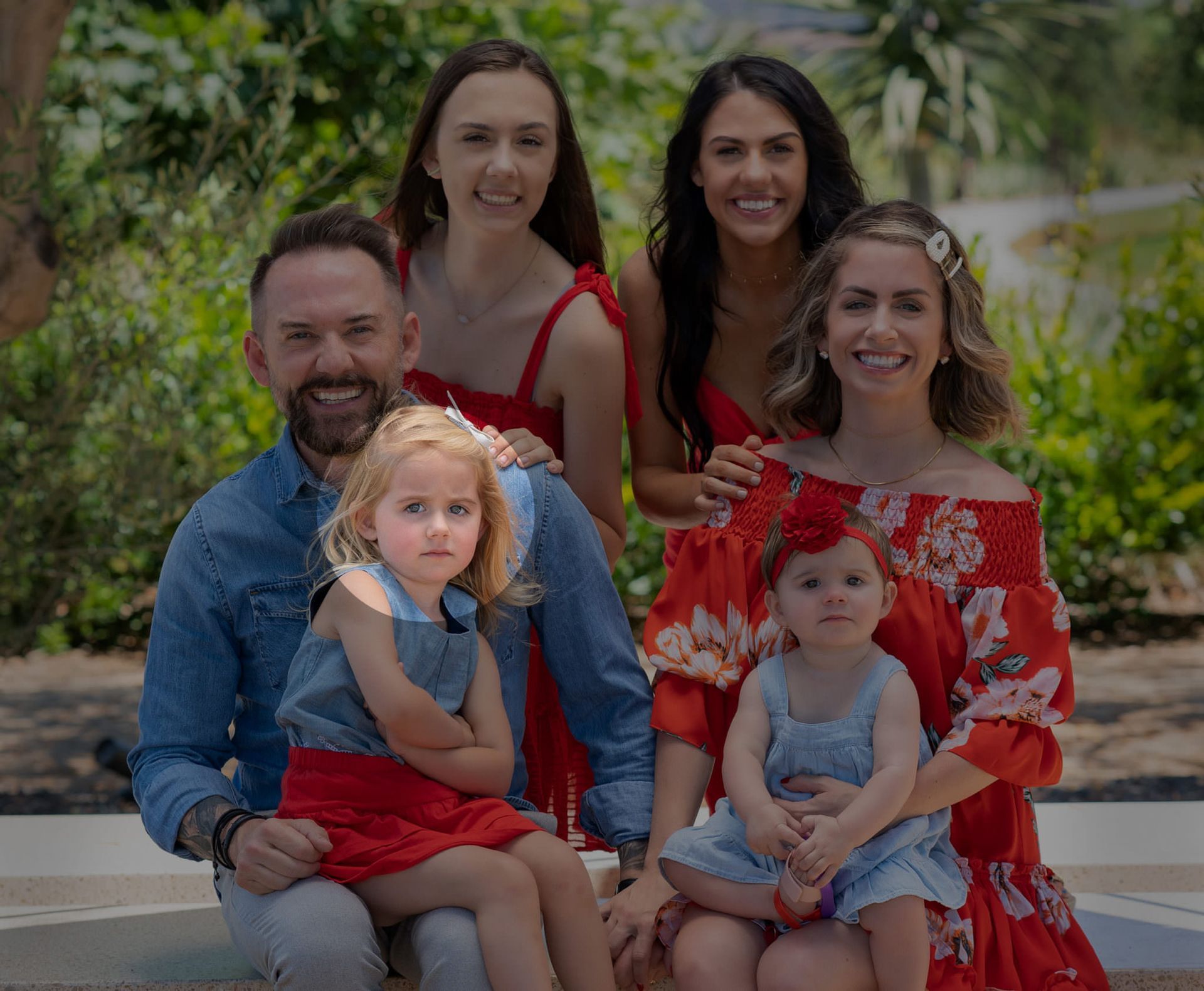 A family is posing for a picture together while sitting on a bench.