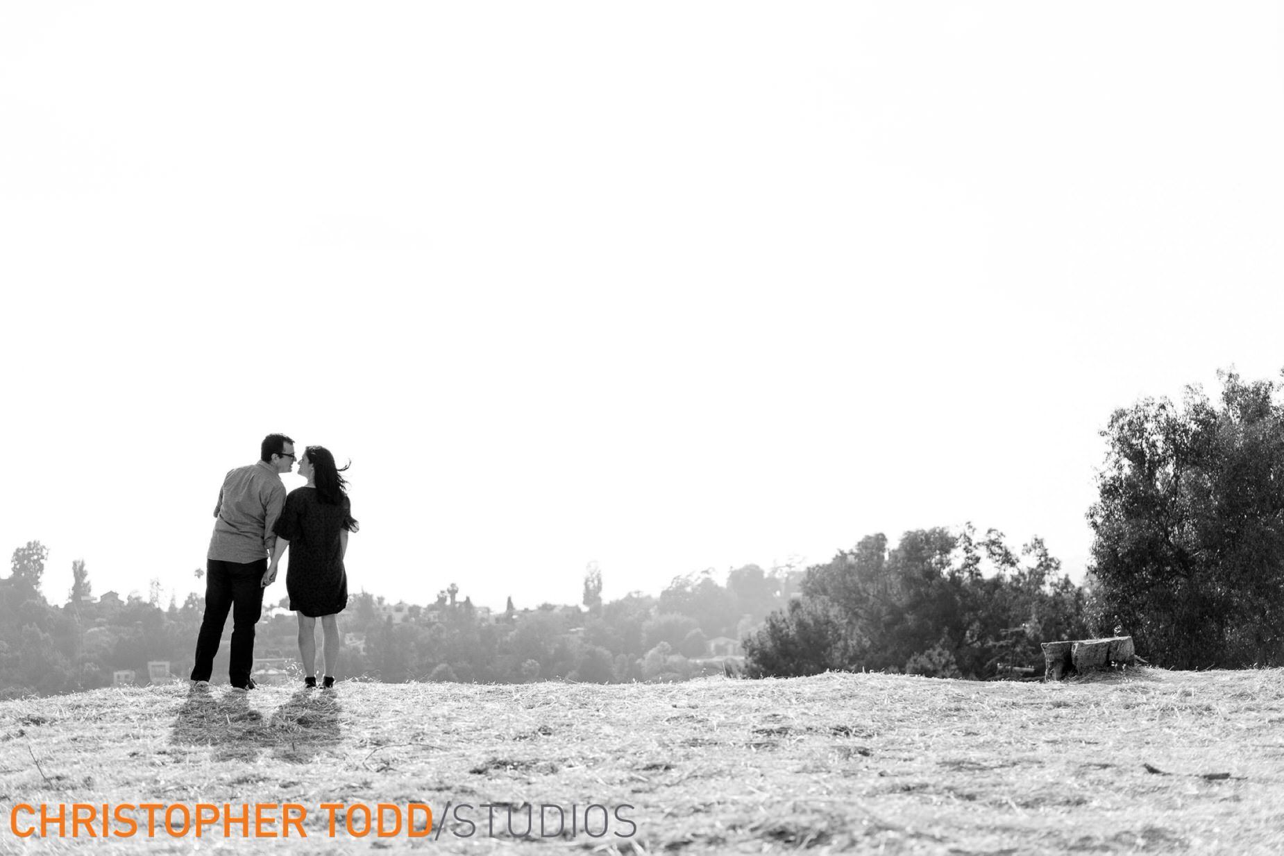 A black and white photo of a man and woman standing on top of a hill.