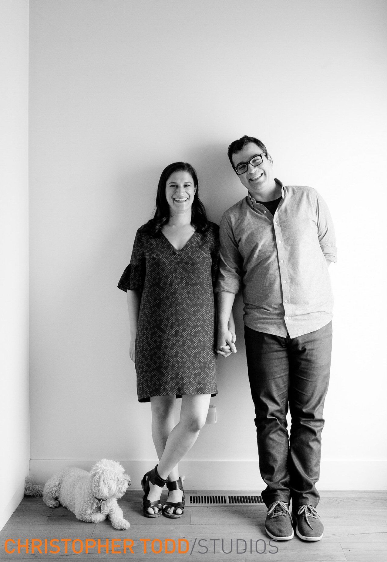 A man and a woman are standing next to each other in a room with a dog.
