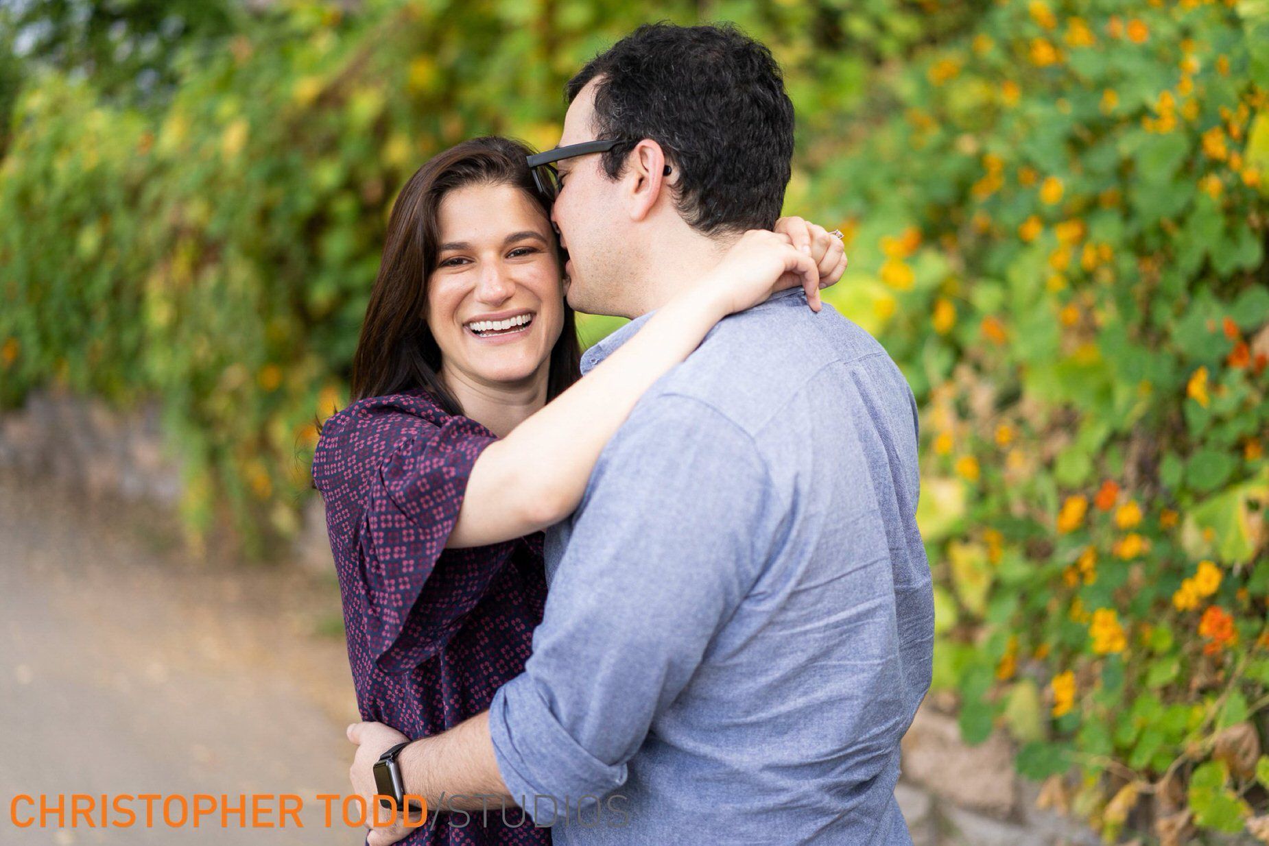 A man is kissing a woman on the cheek while they are hugging.