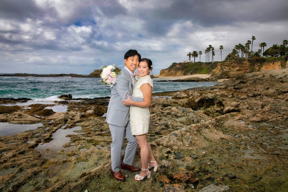 A bride and groom are posing for a picture on at the tide pools in Laguna Beach