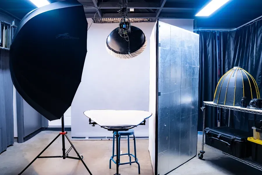 A photo studio with a table , stools , and lights.