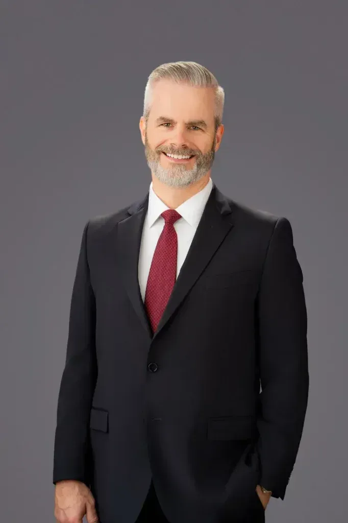 A man in a suit and tie is standing with his hands in his pockets.