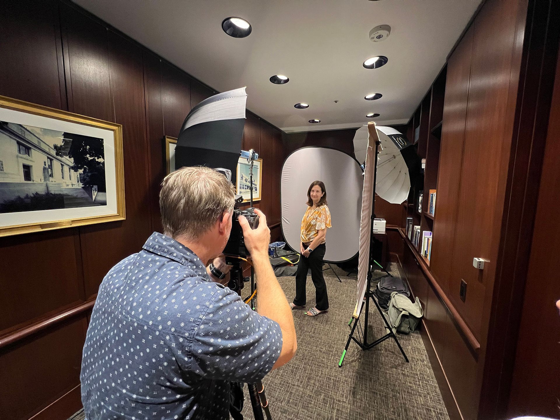 Photographer taking a photo of a person posing in a hallway with studio lighting.