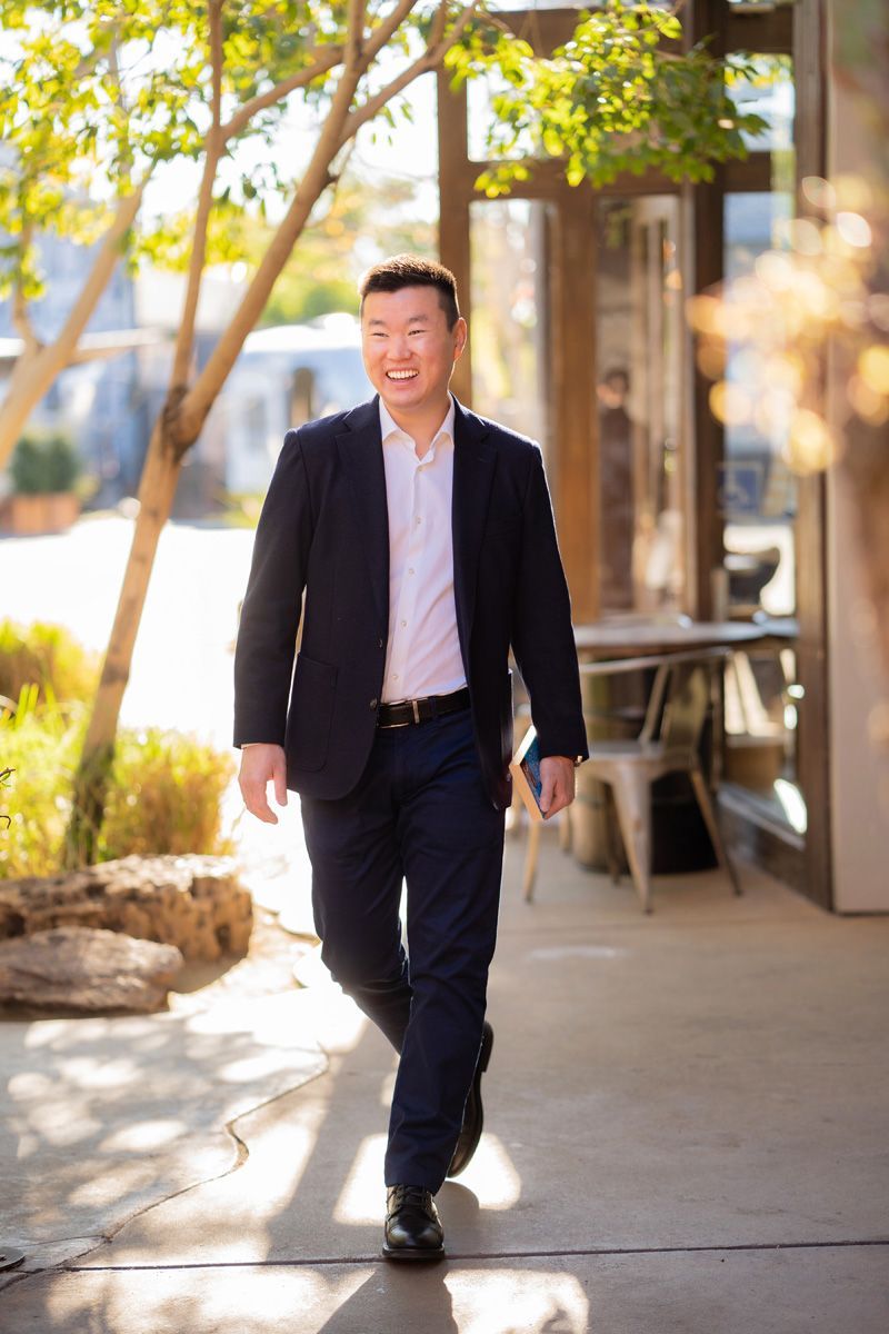 A man in a suit and white shirt is walking down a sidewalk for a Tinder app photo