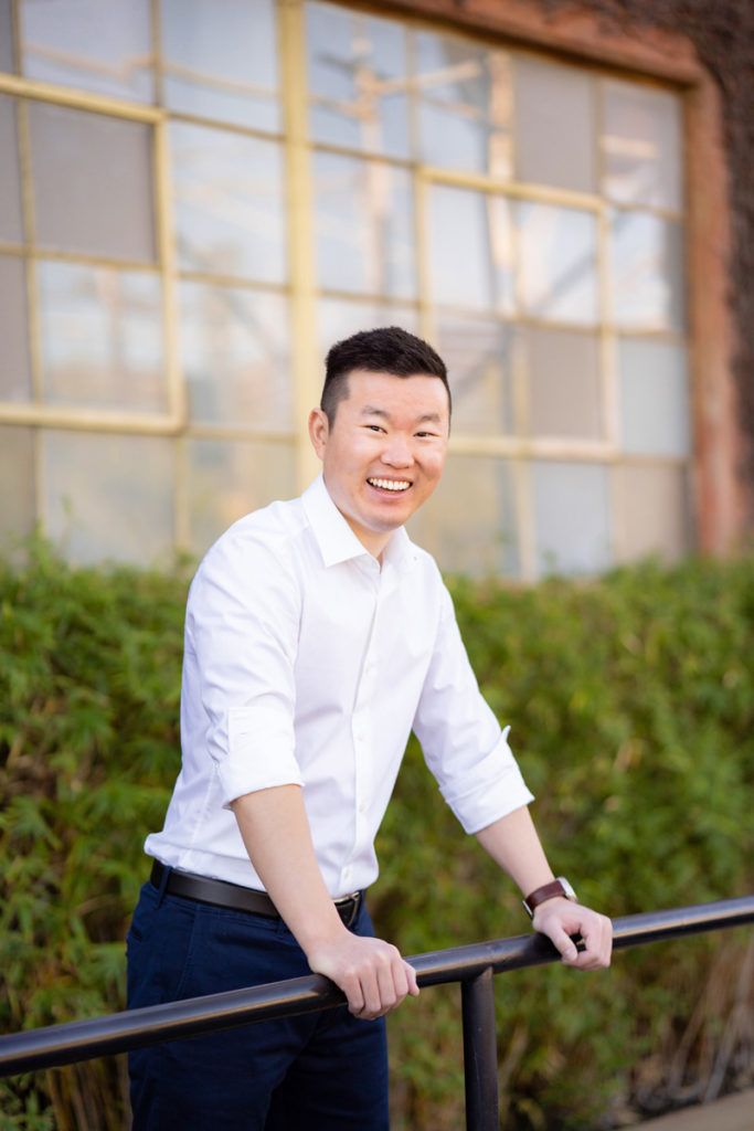 A man in a white shirt and blue pants is leaning on a railing.