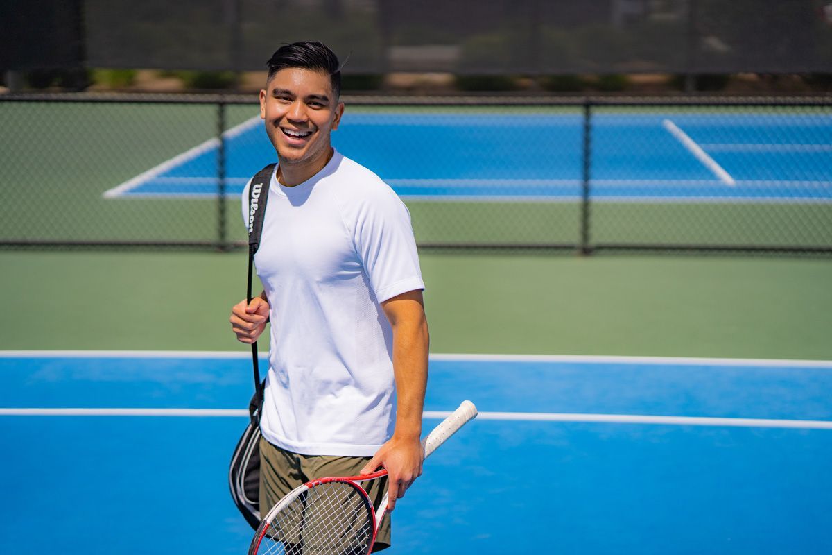 A man is holding a tennis racquet on a tennis court costa mesa. 