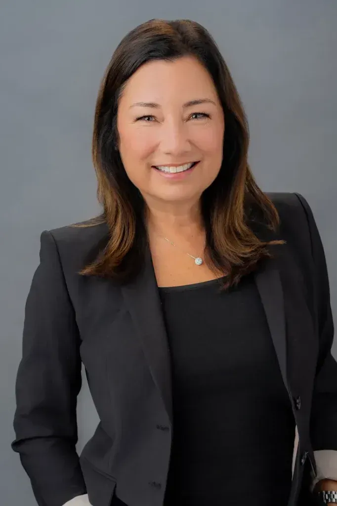 A woman in a black jacket and black shirt is smiling for the camera.
