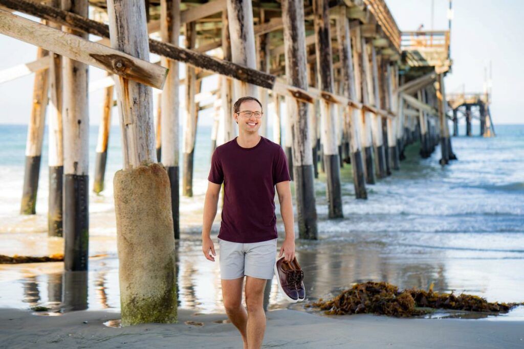 A man is walking under the Newport Beach pier.