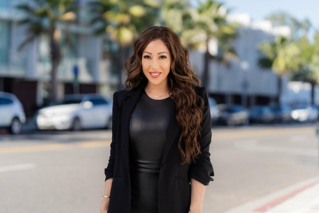 Newport Beach Branding Session A woman in a black dress and blazer is standing on a sidewalk.