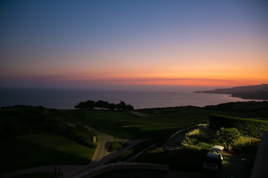 A sunset over a Laguna Beach with a golf course in the foreground.