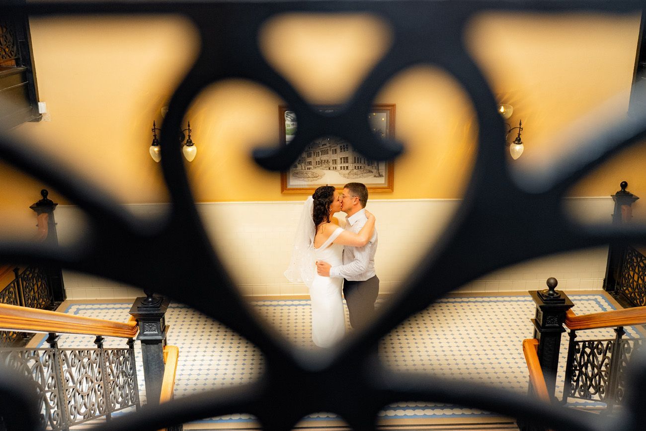 A bride and groom kissing through a heart-shaped fence at the historic courthouse in Orange County. 