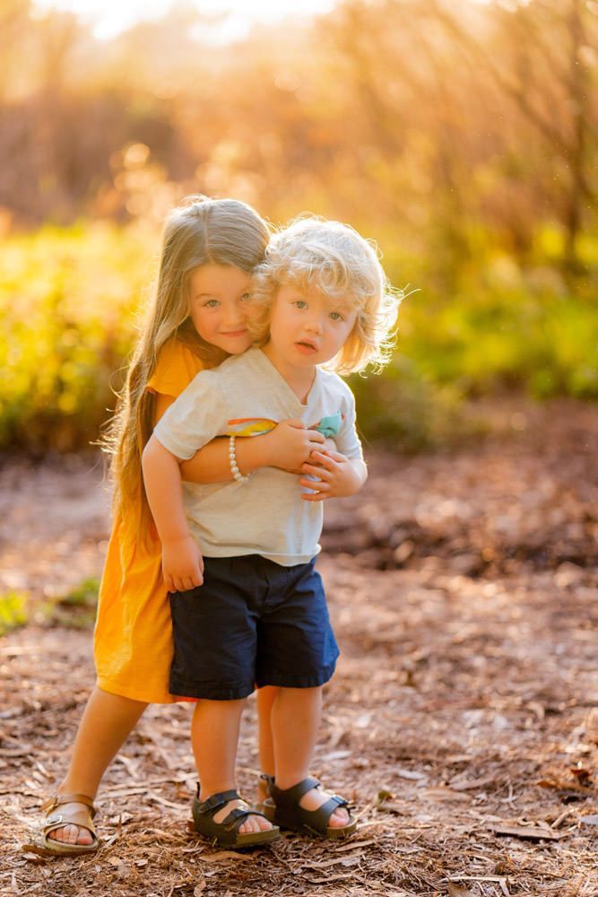 A little girl is hugging her brother in a field.