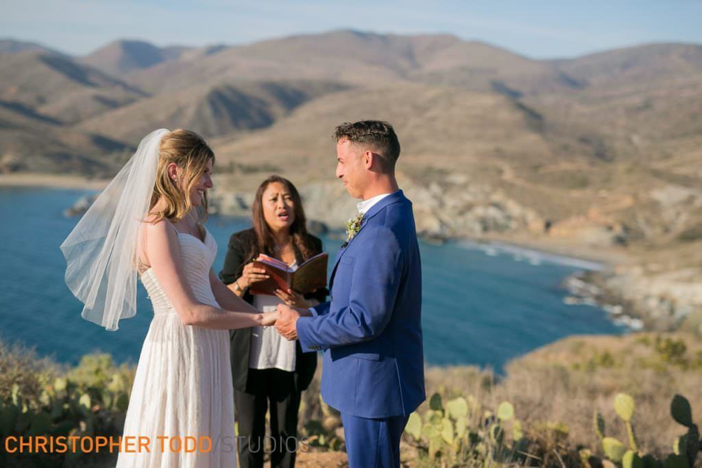 A bride and groom are getting married on top of a hill overlooking the ocean on Catalina Island.