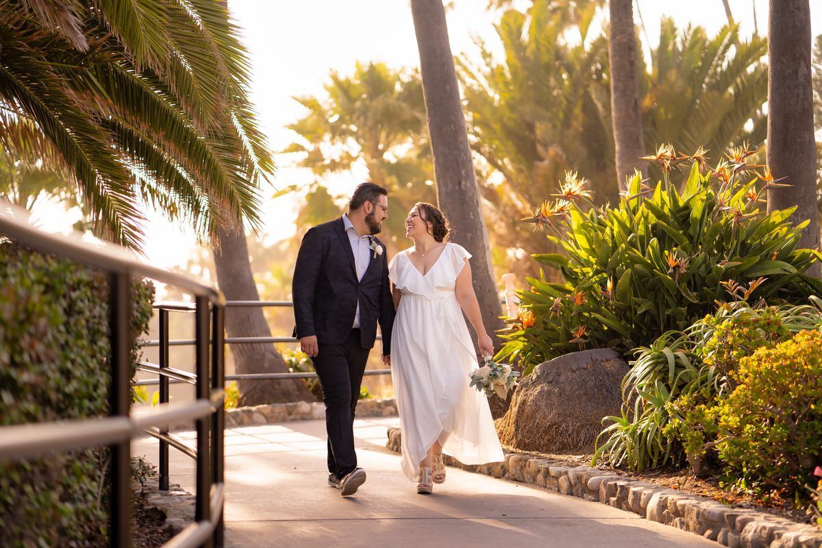 A bride and groom are walking next to the Heisler Park gazebo before their wedding